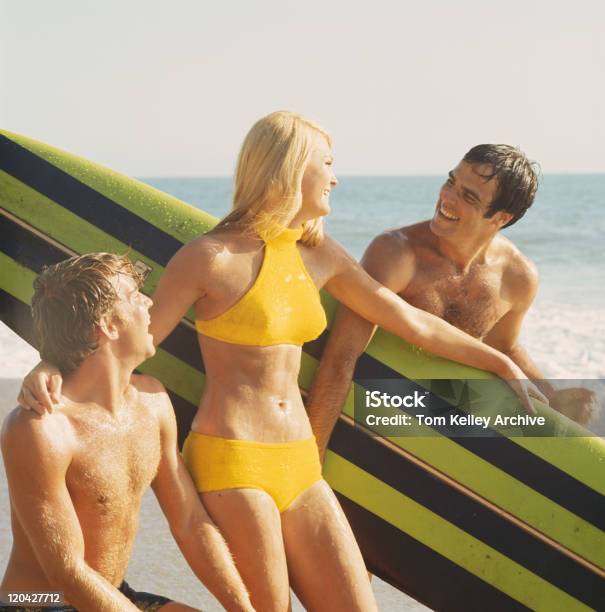 Giovane Uomo E Donna Con Tavola Da Surf Sulla Spiaggia Sorridente - Fotografie stock e altre immagini di Di archivio