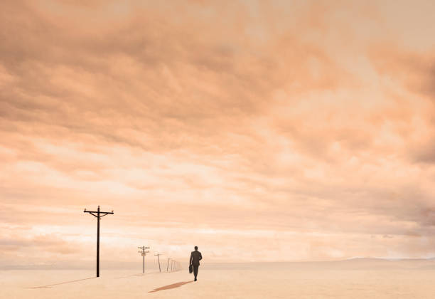 istock Businessman On Dusty Plain Lined With Telephone Poles 1204277337