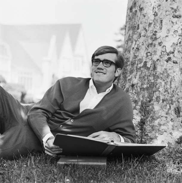 jovem inclinar-se contra árvore segurando um livro, sorrir - 1969 imagens e fotografias de stock