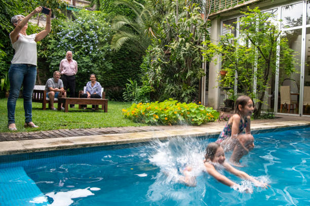 istock Two girls jumping into a pool in a back yard 1204277832