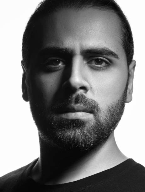 istock Vertical black and white head shot of middle eastern guy on white background 1204279003