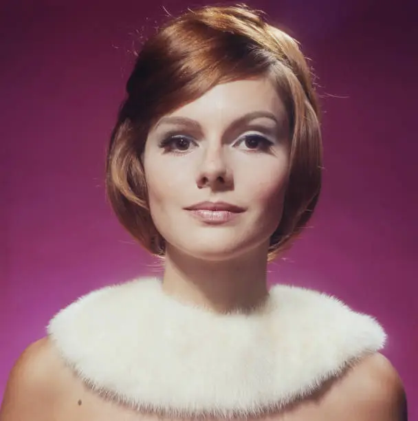 Photo of Young woman wearing fur against pink background, close-up, portrait
