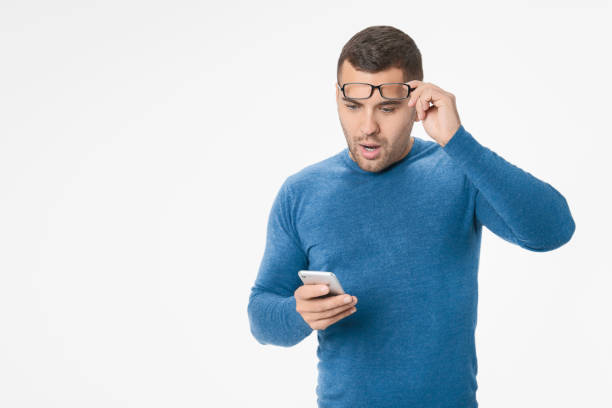 istock Shocked young man looking and celebrating at mobile phone isolated over white background 1204282079