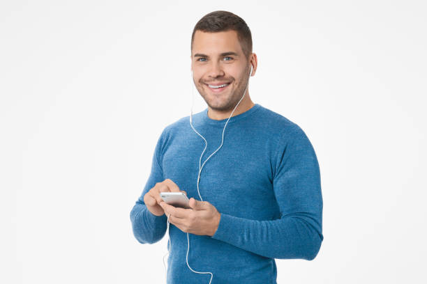 istock Excited smiling man wearing earphones while using mobile phone isolated over white background 1204282098