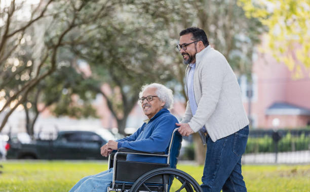 istock Hispanic man pushing senior father in wheelchair 1204282421