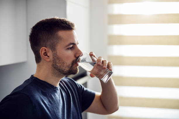 istock Side view of handsome thirsty man drinking fresh water. Home interior. 1204283127