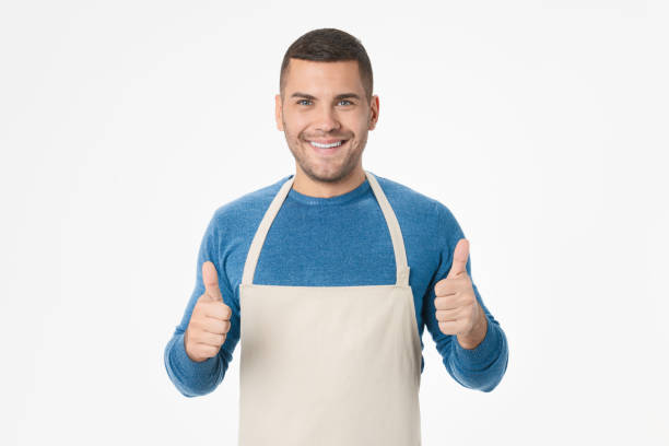 istock Young handsome shopkeeper man wearing apron doing thumbs up gesture standing over isolated white background 1204283237