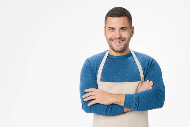 istock Young handsome shopkeeper man wearing apron standing over isolated white background 1204283239