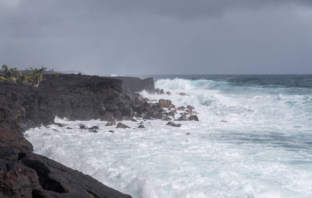 Azure wave crashes on black lava coast at Kaimu Beach, Hawaii, USA.