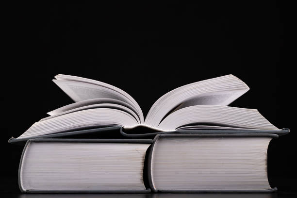 istock An open thick book on a stack of other books. Extensive books preparation for reading and analysis. Dark background. 1204285862