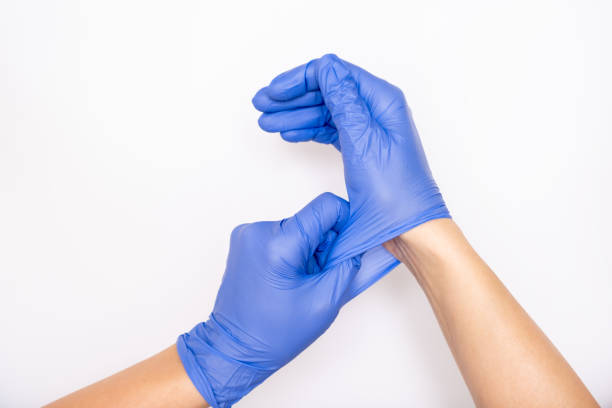 arzt oder krankenschwester setzen auf blaue nitril chirurgische handschuhe, professionelle medizinische sicherheit und hygiene für die chirurgie und medizinische untersuchung auf weißem hintergrund - handschuh stock-fotos und bilder