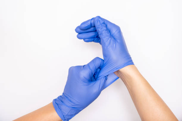 doctor or nurse putting on blue nitrile surgical gloves, professional medical safety and hygiene for surgery and medical exam on white background - disposable imagens e fotografias de stock