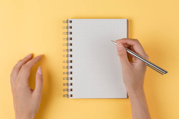 istock girl writes in an open notebook, yellow background 1204291006
