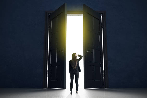 istock Decision making concept with businesswoman standing in front of doors in abstract bright space. 1204293438