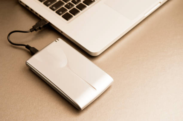 istock external hard drive with laptop, on gilt metal table.top view 1204299433