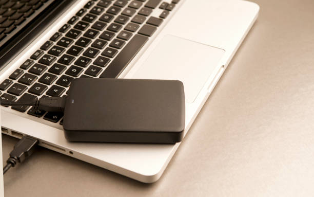 istock black external hard drive, laptop, on gilt metal table.concept office. 1204299445