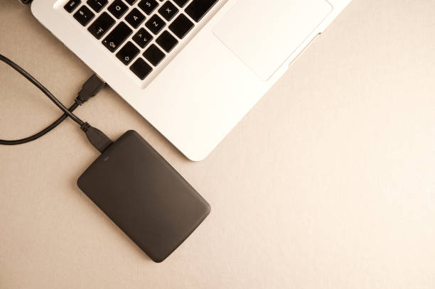 istock black external hard drive, laptop, on gilt metal table.concept office.top view 1204299464