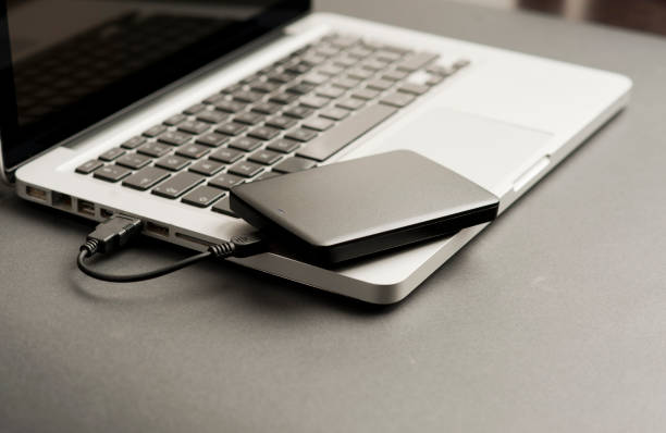istock external hard drive black on laptop, on black office table.Top view 1204299483