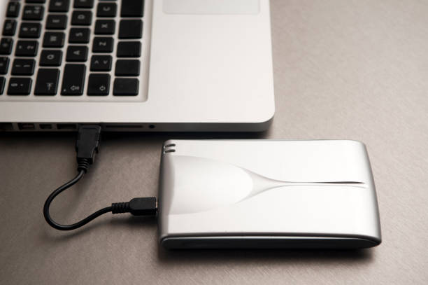 istock silver external hard drive, partial laptop view, on aluminum table 1204299499