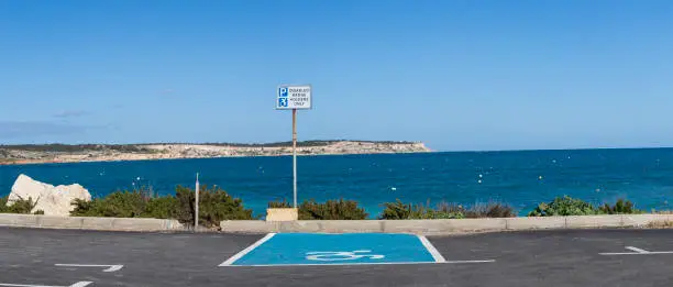 Photo of Handicapped parking spot with disability symbol painted in bright blue and white on the asphalt