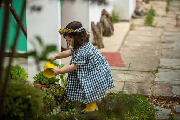 Cute little girl watering plant in back yard