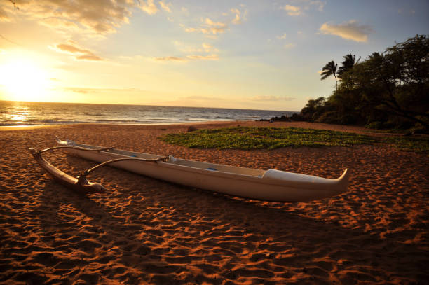 Canoe on beach in Maui Outrigger canoe on a sandy beach at sunset in Maui Hawaii outrigger stock pictures, royalty-free photos & images