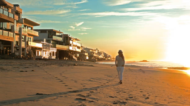 woman walking on beach at sunset - horizon over water malibu california usa imagens e fotografias de stock