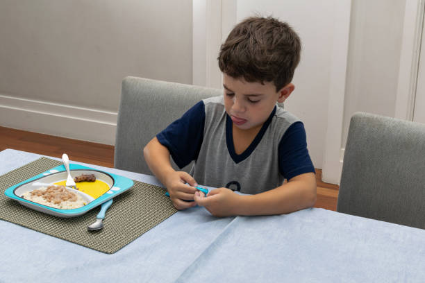 저녁 식사 시간에 파란색 점액을 가지고 놀고 있는 6 살 짜리 소년. - eating cereal student human mouth 뉴스 사진 이미지