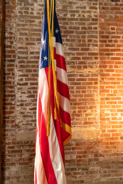 istock American Flag on Stand, against old brick wall, with copy space. 1204319877