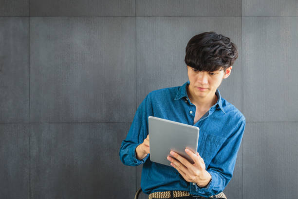istock Portrait of young Asian Business man using digital tablet computer on gray background 1204319982