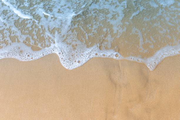 istock White wave on brown sand beach, nature background 1204319999
