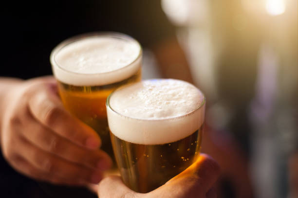 cheers! clink glasses. close-up shots of hands holding beer glasses and beer bubbles. - beer imagens e fotografias de stock