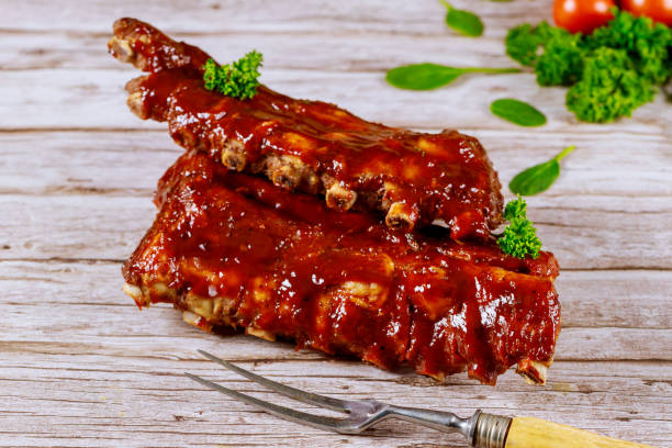 istock Beef ribs with barbecue sauce and fork on wooden board. 1204332245