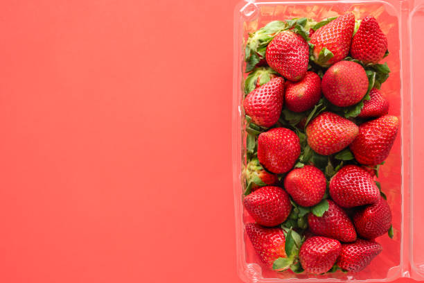 istock Fresh ripe organic strawberries in plastic container close up on red background, view from above, copy space 1204339332