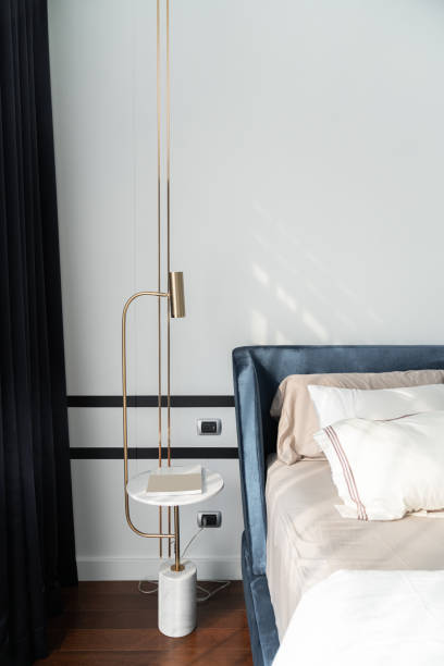 istock Bedroom corner navy blue velvet bed with soft pillows setting decorated with circular marble night table and navy blue paint wall in the background / cozy interior design 1204339668