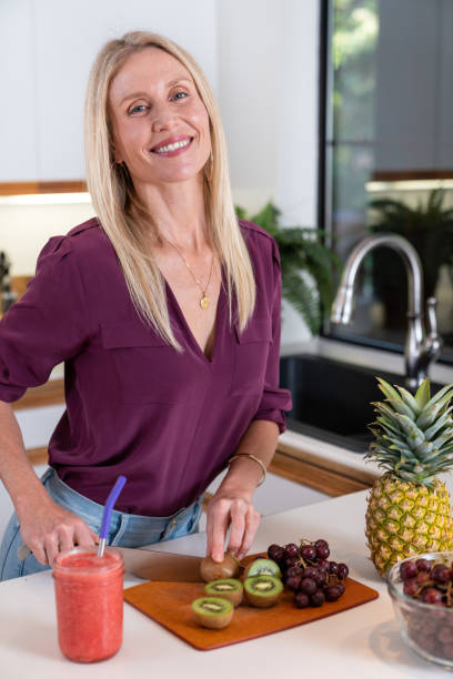 istock Woman cutting fruit in kitchen 1204339696