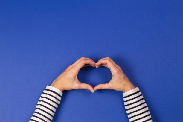 istock Woman hands making heart shape on blue background. Top view 1204347514