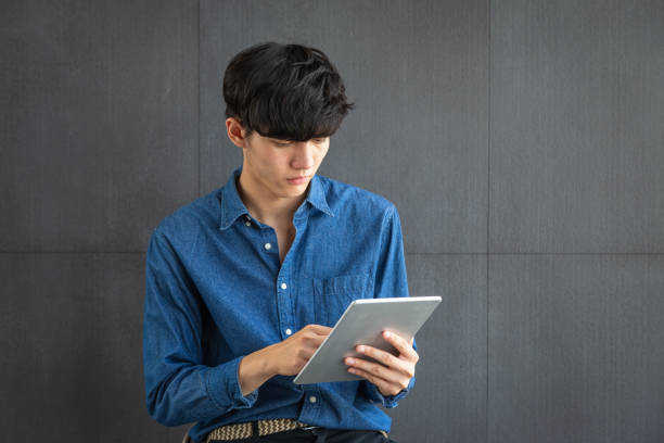 istock Portrait of young Asian Business man using digital tablet computer on gray background 1204348442