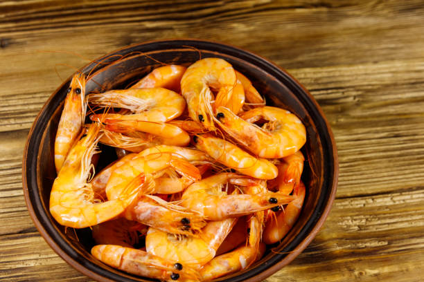 istock Fresh raw shrimps in a ceramic bowl on a wooden table 1204348518