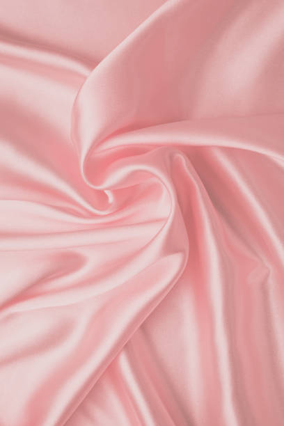 istock Pastel soft pink background, silk fabric pattern. Abstract light wallpaper with waves of luxury textile. Smooth glossy cloth, satin texture with folds. 1204359687
