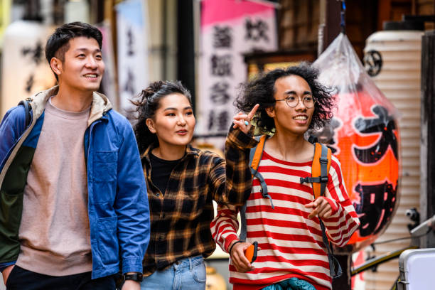 istock Three multi racial friends walking down street and talking 1204359696