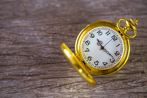 vintage golden pocket watch over wooden floor background,Image for time management concept.