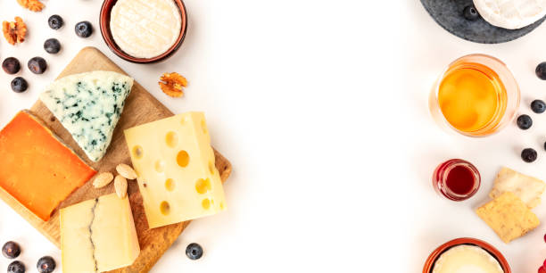 istock Cheese panoramic background, a top shot on white with copy space. An assortment of cheeses with wine and fruits, a design template for a banner 1204359837