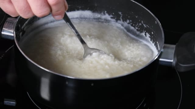 Male hand stirring rice in a pot