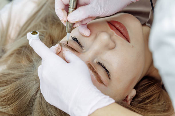 istock Permanent makeup, tattooing of eyebrows. Cosmetologist applying make up 1204362283