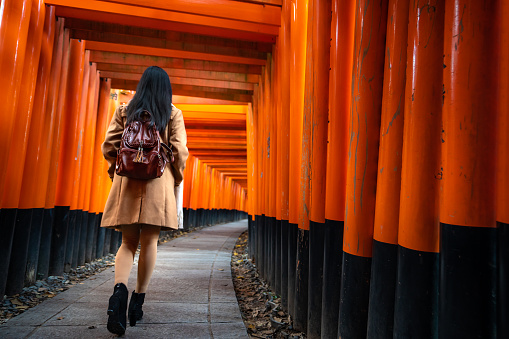 Kyoto, Japan - November 24,2019 : One Asian woman traveller with backpack walking and sightseeing at famous destination Fushimi Inari Shrine in Kyoto, Japan.