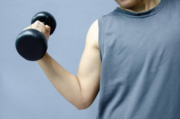 istock Hand  with black dumbbell on gray background in healthty concept. 1204366012