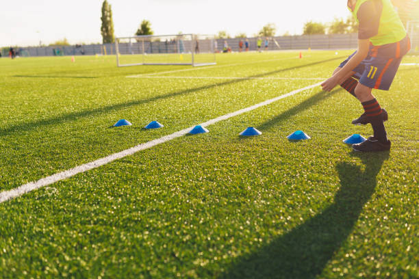 istock Soccer Football Training Run. Young Player Running Fast Between Training Cones Markers on Summer Day. Football Training Stadium in the Background 1204367634