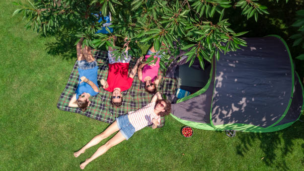 vacances en famille dans la vue aérienne de dessus de camping d’en haut, parents et enfants se détendre et s’amuser dans le parc, la tente et l’équipement de camping sous l’arbre, la famille dans le concept extérieur de camp - tree grass family human relationship family photos et images de collection