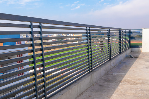 Steel railing on the house traces on blue sky background.